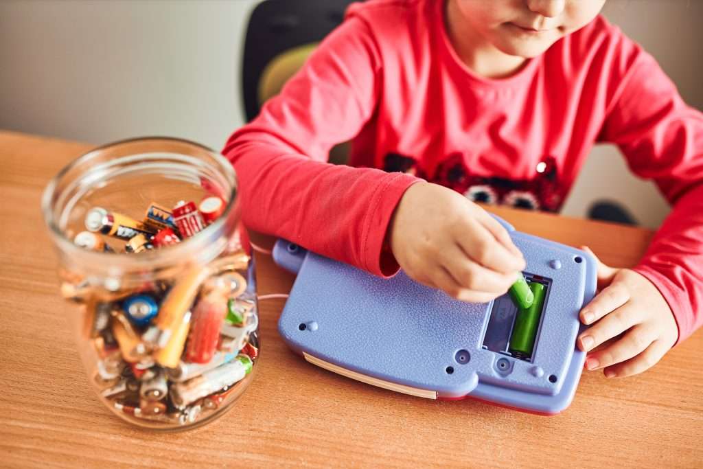 Kleines Mädchen tauscht Batterien an einem Gerät aus. Foto: envato elements