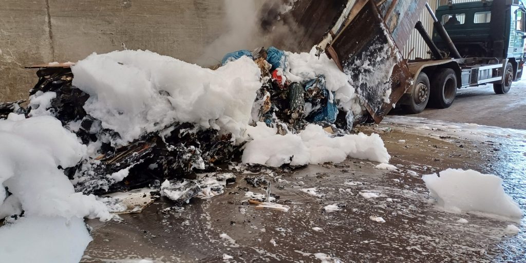 Gelöschter Brand 1 Mit Schaum gelöschter Abfall in einer Umschlaghalle, Auswirkungen nicht ordnungsgemäßer Entsorgung von Elektroschrott