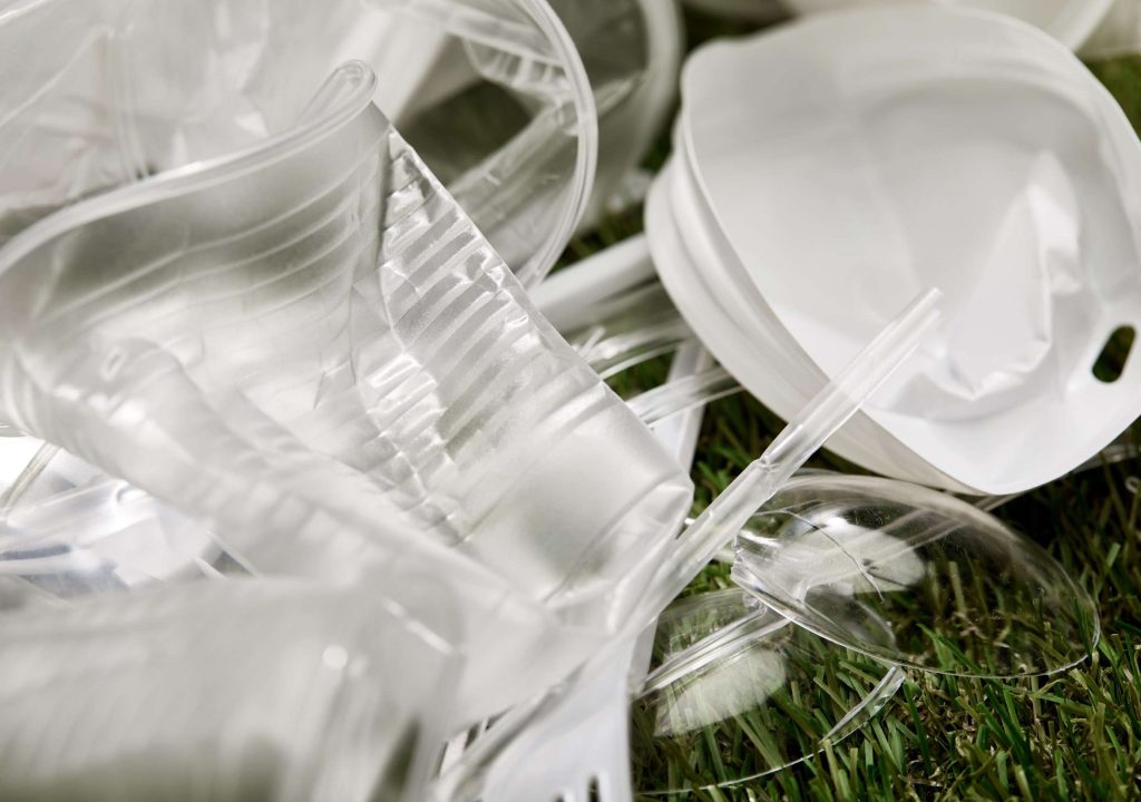 close up view of crumpled plastic cups and rubbish on grass